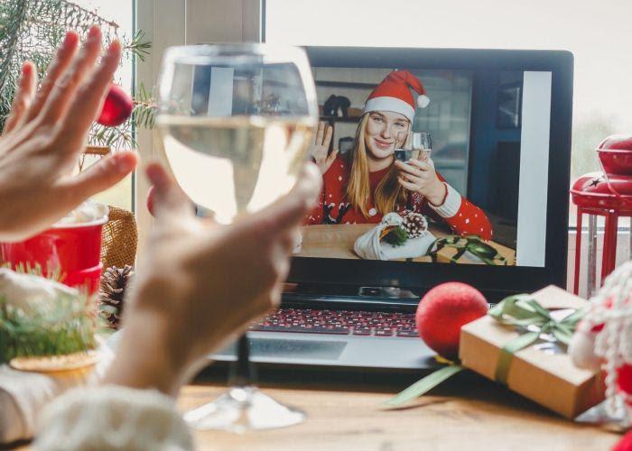 A woman playing a virtual White Elephant, with a glass of wine in her hand.
