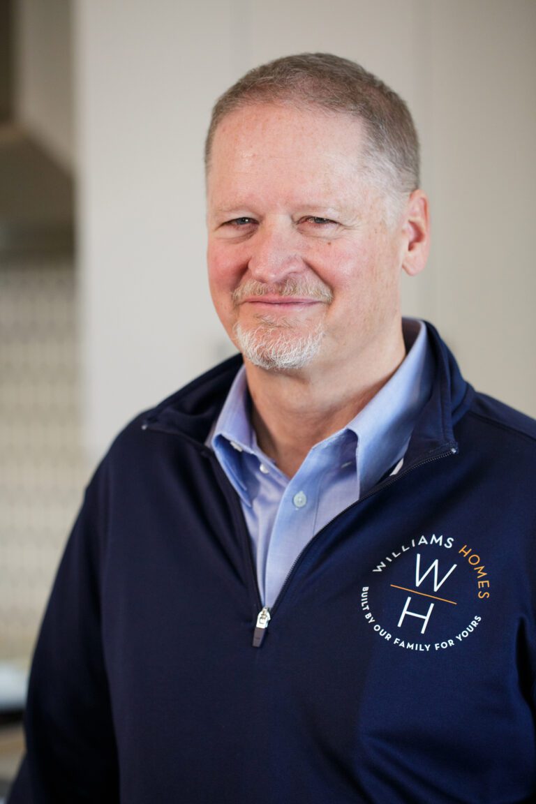 Lance Williams, CEO of Williams Homes, wearing a blue dress shirt and blue pullover sweater with the Williams Homes logo