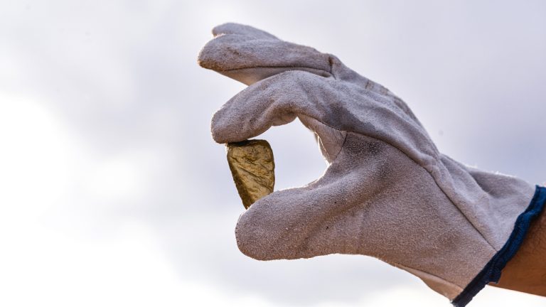 junior mining gold explorer hold gold in hand at mining site
