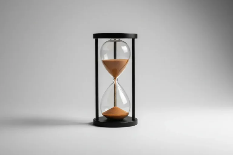 Minimalist hourglass with sand mid-flow on a soft gray background, symbolizing accountability and steady progress.